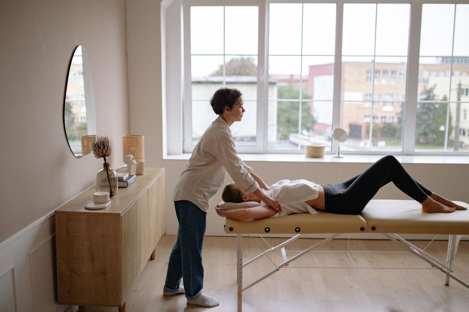 Practitioner working with a patient in a calm, window-lit treatment room